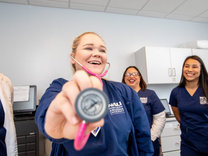 Students smile as they pose with a stethoscope.