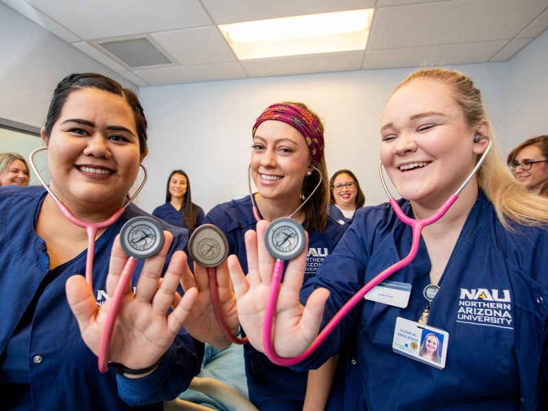 N A U Nursing students hold up their stethoscopes and pose for a photo.