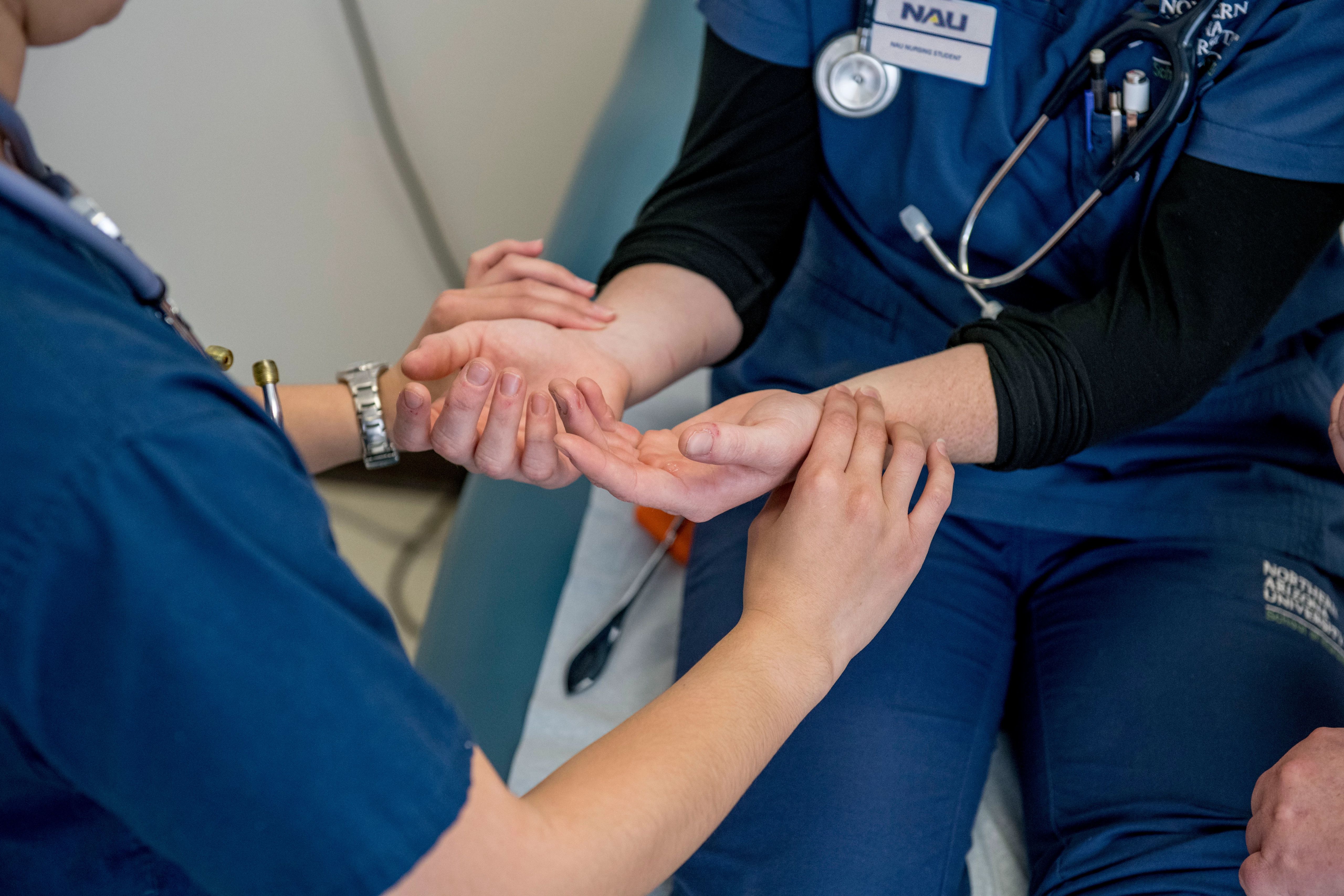 A nursing instructor at N A U demonstarates checking a patients vitals.