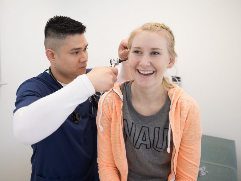 A nursing student at N A U practices screening for ear problems on another student.