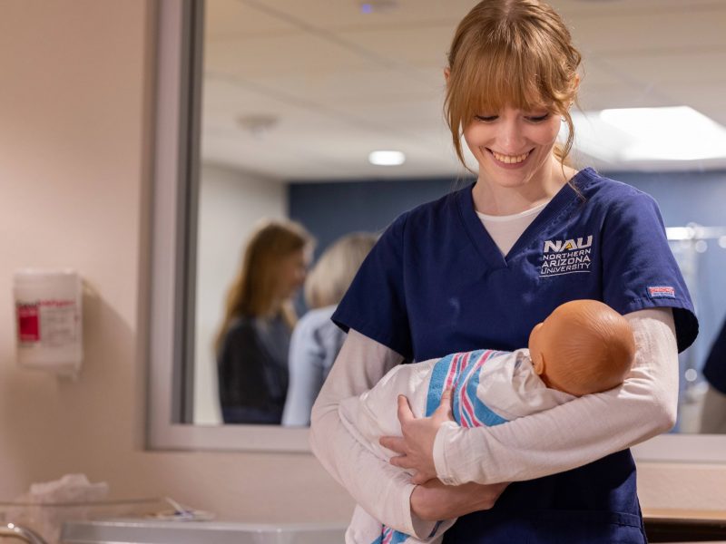 A nursing student at N A U practices holding a baby.