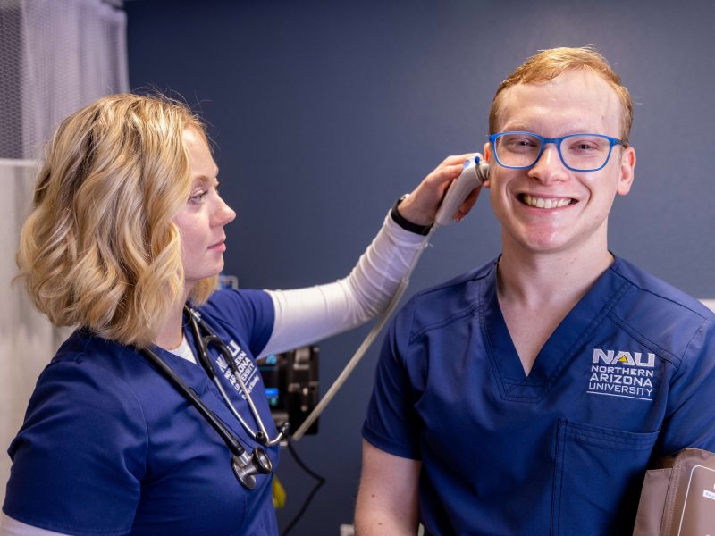 A nursing student at N A U practices screening for ear problems on another student.