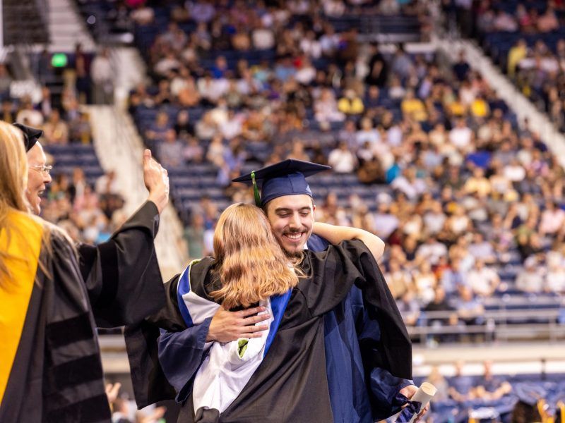 A student smiles and hugs faculty at N A U commencement.