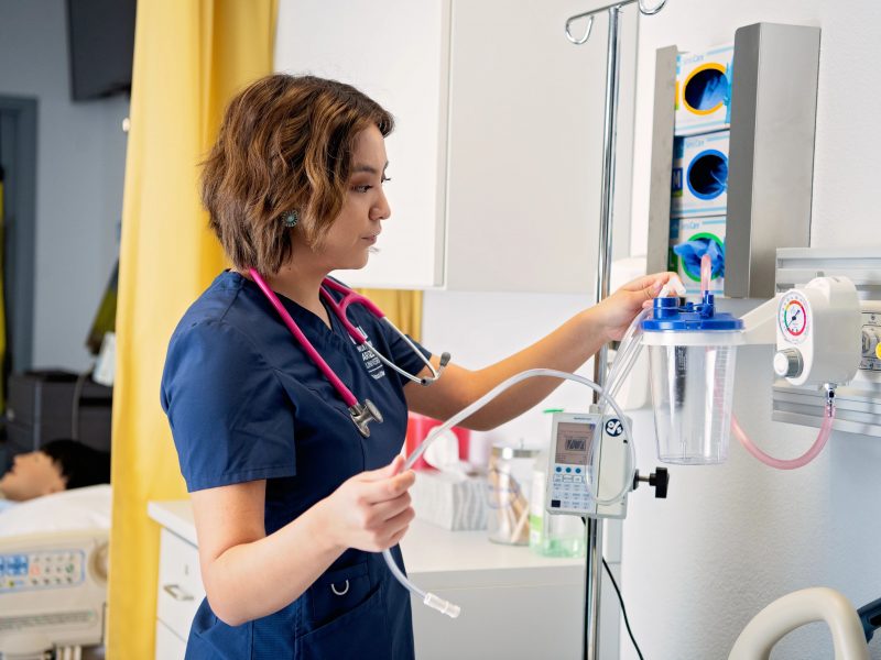 A Northern Arizona University nursing tudent working in a patient room.