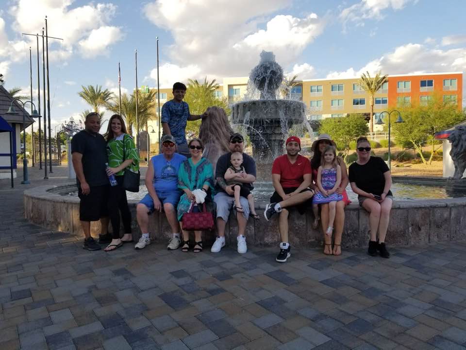 Group of people sitting in front of a fountain smiling. 