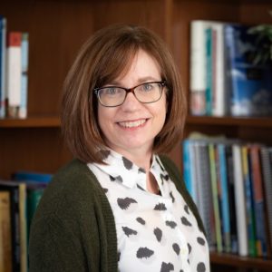 Photo of Dr. Ronda Jenson standing in front of bookshelves