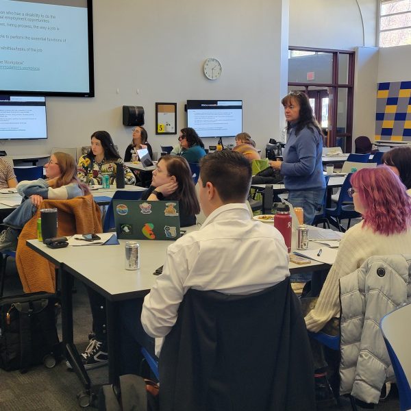 Group of youth and adults in a large classroom with computer monitors