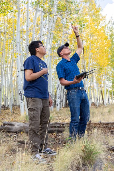 Kenny with Dr. Fulé who is holding a drone remote. Both people are looking into the sky 