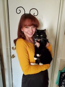 Lorissa smiling at camera holding a black cat