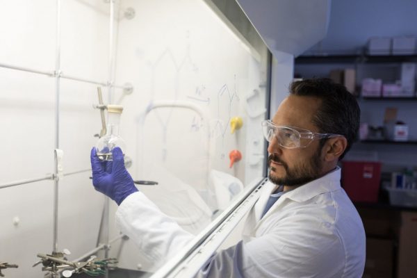 Researcher working in fume hood with beaker