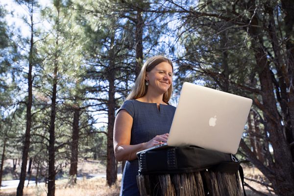 Julie Mueller conducting work on a computer in a forest