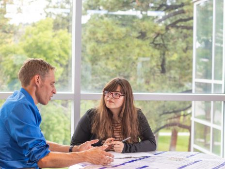 Dirk de Heer works with a student on a poster presentation.