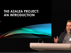 A photo of Dr. Megan McCoy introducing the AZALEA project. She has medium length brown hair. There is text on a projected screen that reads "The AZALEA PROJECT INTRODUCTION"
