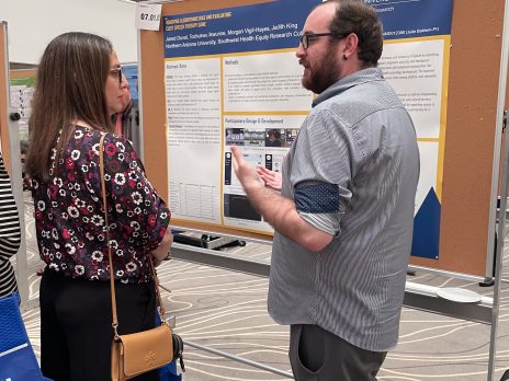 Jared presents a poster to a conference attendee.